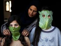 أم فلسطينية ترفه عن أطفالها بأقنعة مصنوعة من الملفوف أثناء الطهي، نيسان 2020