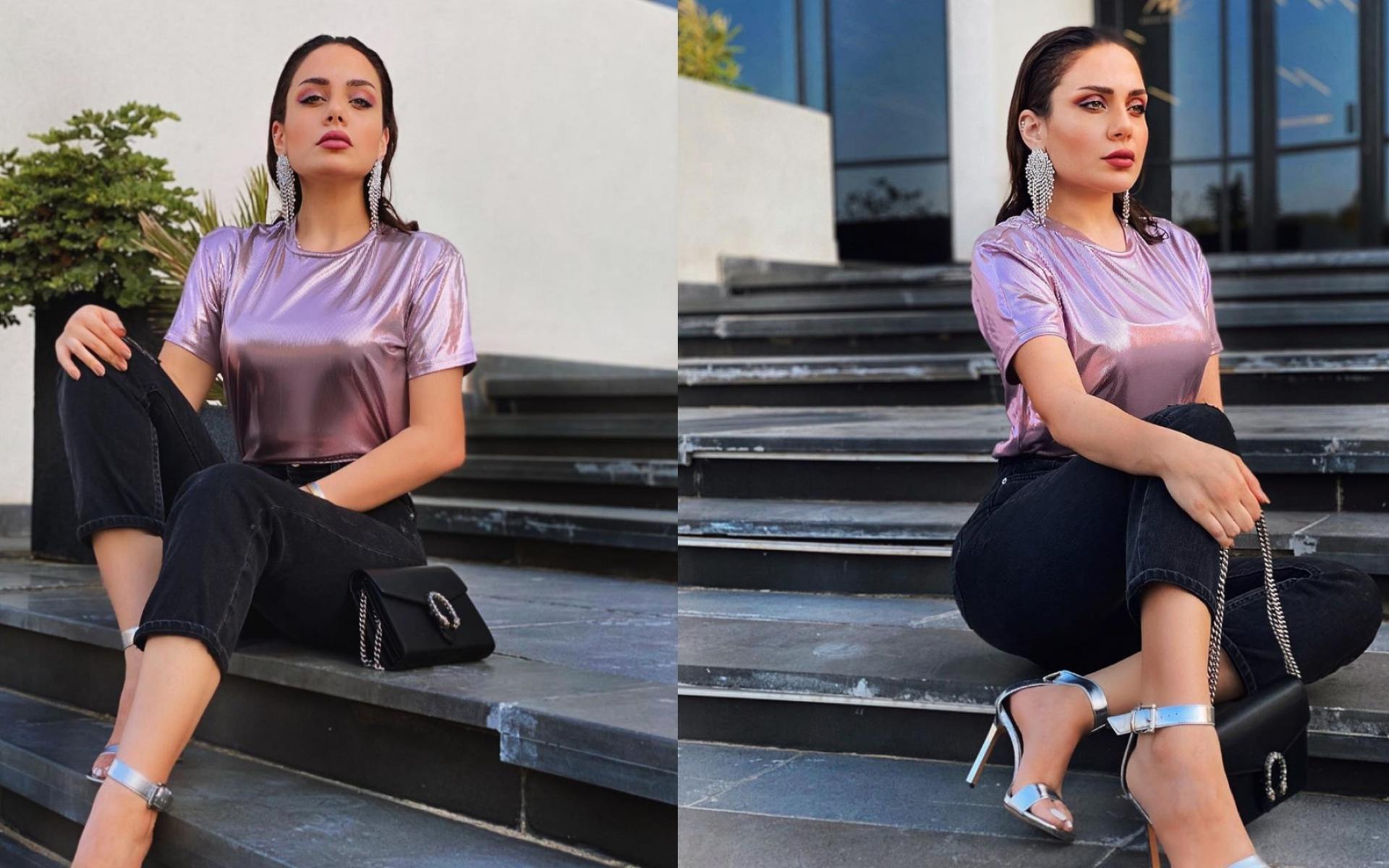 إطلالة عصرية جريئة مكونة من توب ذهبي وبنطلون أسود وعقد كبير أيضاً باللون الذهبي، مع إعتماد تسريحة الشعر المبلل