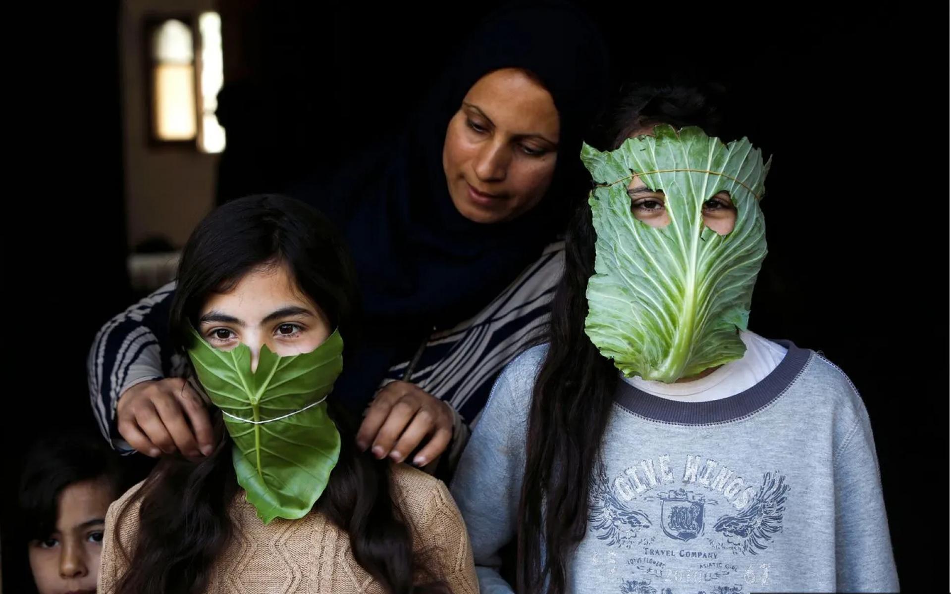 أم فلسطينية ترفه عن أطفالها بأقنعة مصنوعة من الملفوف أثناء الطهي، نيسان 2020 أم فلسطينية ترفه عن أطفالها بأقنعة مصنوعة من الملفوف أثناء الطهي، نيسان 2020